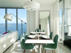 een eetkamer met een tafel en groene stoelen bij MVR An Unforgettable View Awaits You in Miami