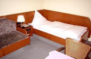 a hotel room with a bed and a chair and a table at Hotel Goldinger in Landstuhl