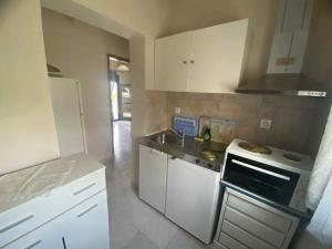 a kitchen with white cabinets and a sink and a stove at Eleftheria House in Vourvourou