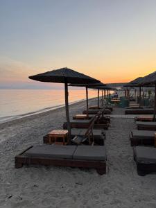 a group of chairs and umbrellas on a beach at G&S Dionisiou Apartment in Paralia Dionysiou