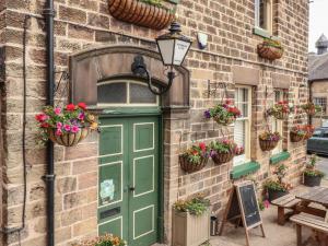 eine grüne Tür in einem Backsteingebäude mit Topfpflanzen in der Unterkunft Milford Cottage in Belper
