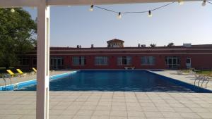 a swimming pool in front of a red building at Hotel Colonial ciudad LABOULAYE in Laboulaye