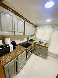 a small kitchen with white cabinets and a sink at Cataleya Apartment in Cullera