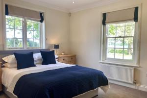 a bedroom with a blue and white bed and two windows at Telegraph House by inspirestays-com in Chichester +52 photos