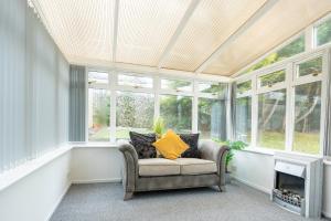 a conservatory with a chair in a room with windows at Ferguson House in Airdrie
