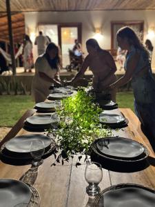 a group of people standing around a wooden table with plates at Casita Beach House in Itarema