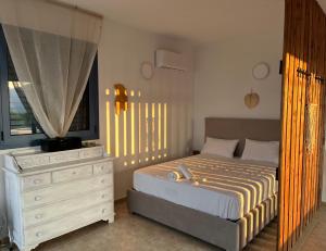 a bedroom with a bed with a dresser and a window at Villa Thea - Τhe View 1st floor in Áno Yerakaríon