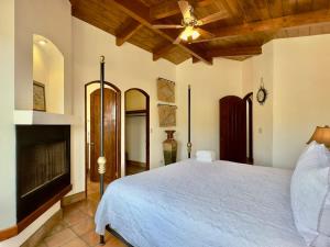 a bedroom with a white bed and a fireplace at Puerto Nuevo Surf Villa Tranquilidad 2BR with pool in Raulis