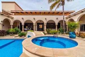 a pool in front of a house with a palm tree at Elegant Hacienda Villa for 20, Ocean Views, Pool in San José del Cabo