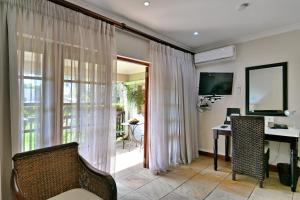 sala de estar con silla, escritorio y TV en Rivonia Premier Lodge, en Johannesburgo