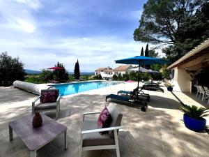 a swimming pool with two chairs and an umbrella at La Rabastide in La Garde-Adhémar
