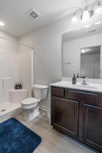 Un baño con inodoro, lavabo y espejo. en Upscale King 3BR Townhouse Mins to Cary & NC State, en Raleigh