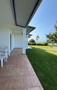 a patio with two white chairs and a green lawn at Physis Seaside Living in Preveza