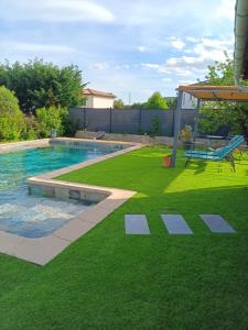 a backyard with a swimming pool and a lawn at L'Annexe in Saint-Martin-de-Valgalgues