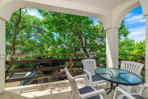 a balcony with a table and chairs and trees at Apartments Bono in Karlobag +55 photos