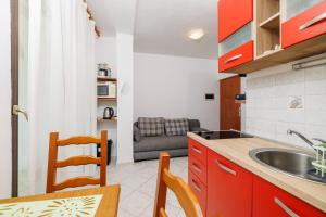 a kitchen with red cabinets and a table and a sink at Apartments Bono in Karlobag