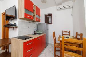 a kitchen with red cabinets and a table and a dining room at Apartments Bono in Karlobag