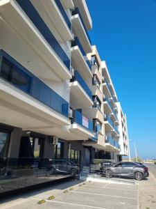a building with cars parked in a parking lot at Sunrise Breeze Apartment in Constanţa