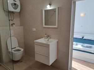 a bathroom with a sink and a toilet and a bed at Apartman Matea in Igrane
