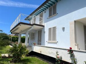 a white house with a blue balcony and a yard at Oasi Blu in Marina di Pietrasanta