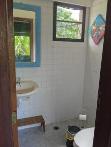 Un baño con lavabo, inodoro y ventana. en Suítes da Malu, en São Sebastião 17 fotos más