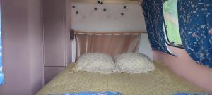 a small bed in a room with a window at carazen , caravane chauffée in Saint-Sylvain-Bellegarde