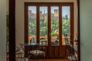 a woman sitting at a table in front of a window at Casa Bombo in Granada