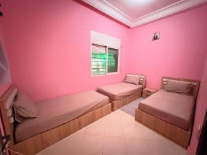a room with two beds and a pink wall at Hassan Apartment - Ideal for Riders, Free Garage Parking Included in Sale