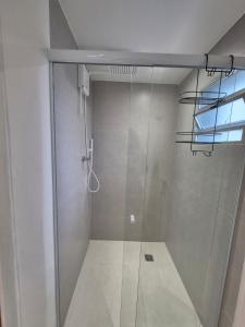 a shower with a glass door in a bathroom at Guaraloft DUBAI Centro de Guarapari in Guarapari +29 photos