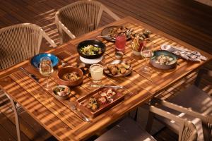 Una mesa de madera con platos de comida encima. en Paraiso de la Bonita Adult All-Inclusive, a Luxury Collection Resort, en Puerto Morelos