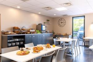 a restaurant with tables and chairs with food on them at All Suites Appart Hôtel - Aéroport Paris-Orly Rungis in Rungis