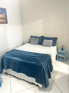 a bedroom with a bed with blue and white sheets at Kitnet aconchegante in Rio das Ostras