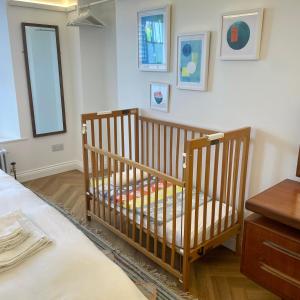 a baby crib in a room with a bed at Ilfracombe Townhouse: restored historic home in Ilfracombe