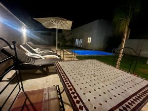 a patio with a table and chairs and an umbrella at Riad Elbahi in Marrakesh