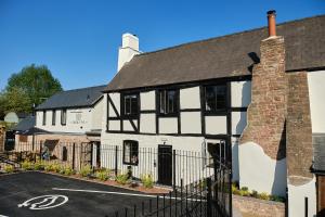 a white and black house with a parking lot at The Crown Inn Lea in Lea