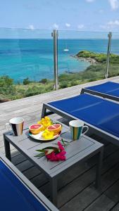 ein Tisch mit einem Teller Obst und Getränken auf einem Deck in der Unterkunft Villa d'Happy Bay - Panoramic View of Caribbean and sunsets in Friar's Bay