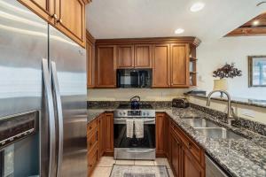 a kitchen with wooden cabinets and a stainless steel refrigerator at Landmark Vail - Charming Condo for 8 with Resort-style Amenities in Vail