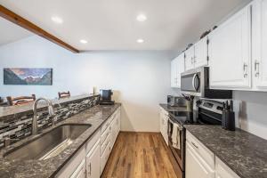 cocina con armarios blancos y fregadero de acero inoxidable en Trail Ridge Retreat - Sleeps 8, en Edwards