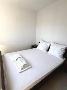 a bed with white sheets and a book on it at Lotus in Donji Štoj