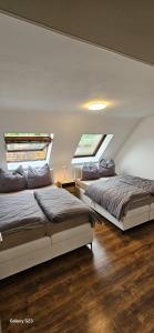 two beds in a bedroom with two windows at Gästehaus Schindhard in Schindhard