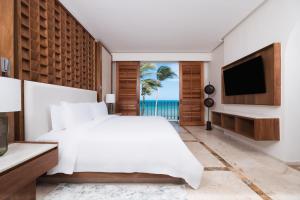 Un dormitorio con una cama blanca y un televisor. en Paraiso de la Bonita Adult All-Inclusive, a Luxury Collection Resort, en Puerto Morelos