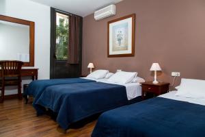 Habitación de hotel con 2 camas con sábanas azules en Hostal LK Barcelona, en Barcelona