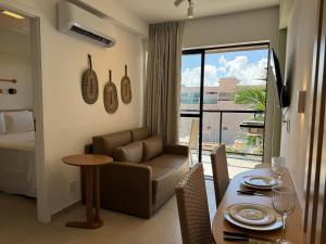a living room with a couch and a table and a bed at Porto Kai Residence Flat Vila de Porto de Galinhas 50m do mar in Porto De Galinhas