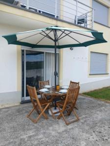 a table with two chairs and an umbrella at Alojamento Luna in Porto Judeu