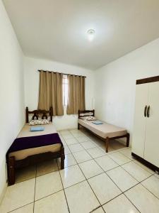a room with two beds and a refrigerator in it at Apartamento mobiliado em Contagem - 2 quartos in Contagem