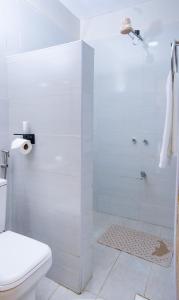 a white bathroom with a shower and a toilet at Adeea Suites Naivasha in Naivasha