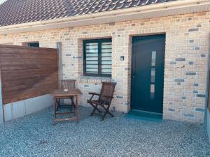 due sedie e un tavolo accanto a un edificio con una porta di Le repaire 3 a Saint-Omer-Capelle