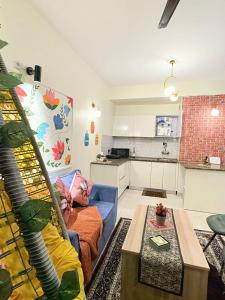 Una sala de estar con un sofá azul y una cocina. en RS Stays, en Noida