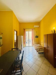 ジャルディーニ・ナクソスにあるLina Houseの黄色の壁の客室で、テーブルと椅子が備わります。