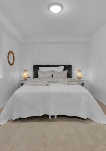 Un dormitorio blanco con una gran cama blanca con dos lámparas. en Åros Modern Apartment, en Kristiansand 35 fotos más